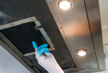 worker cleaning grease from kitchen hood